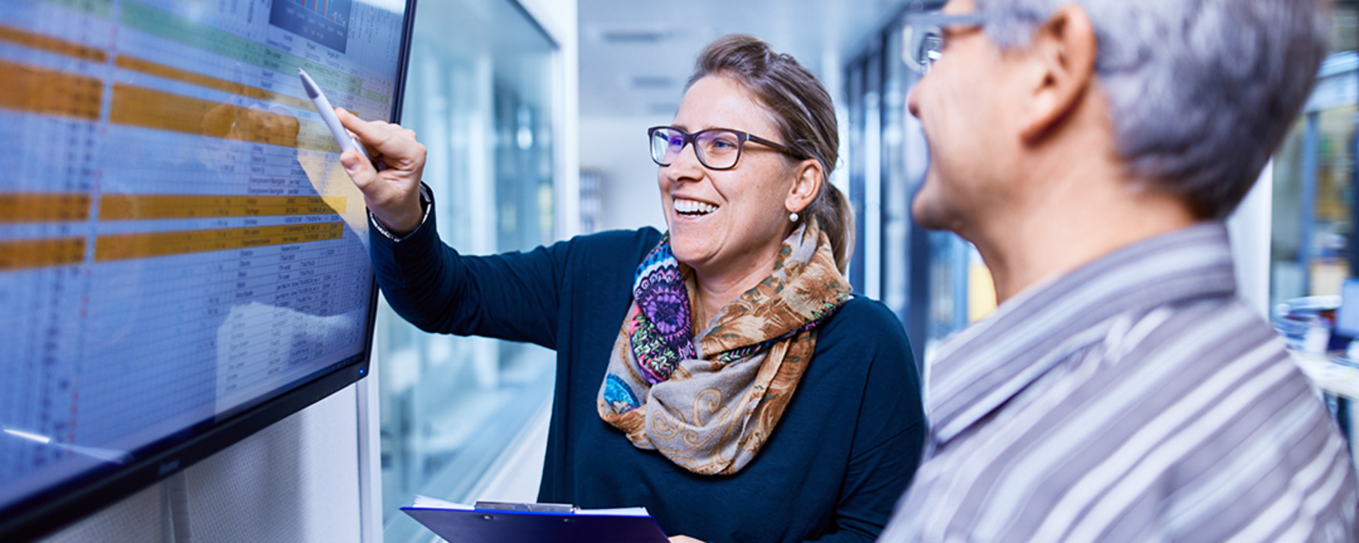 zwei Mitarbeiter stehen vor einem Bildschirm